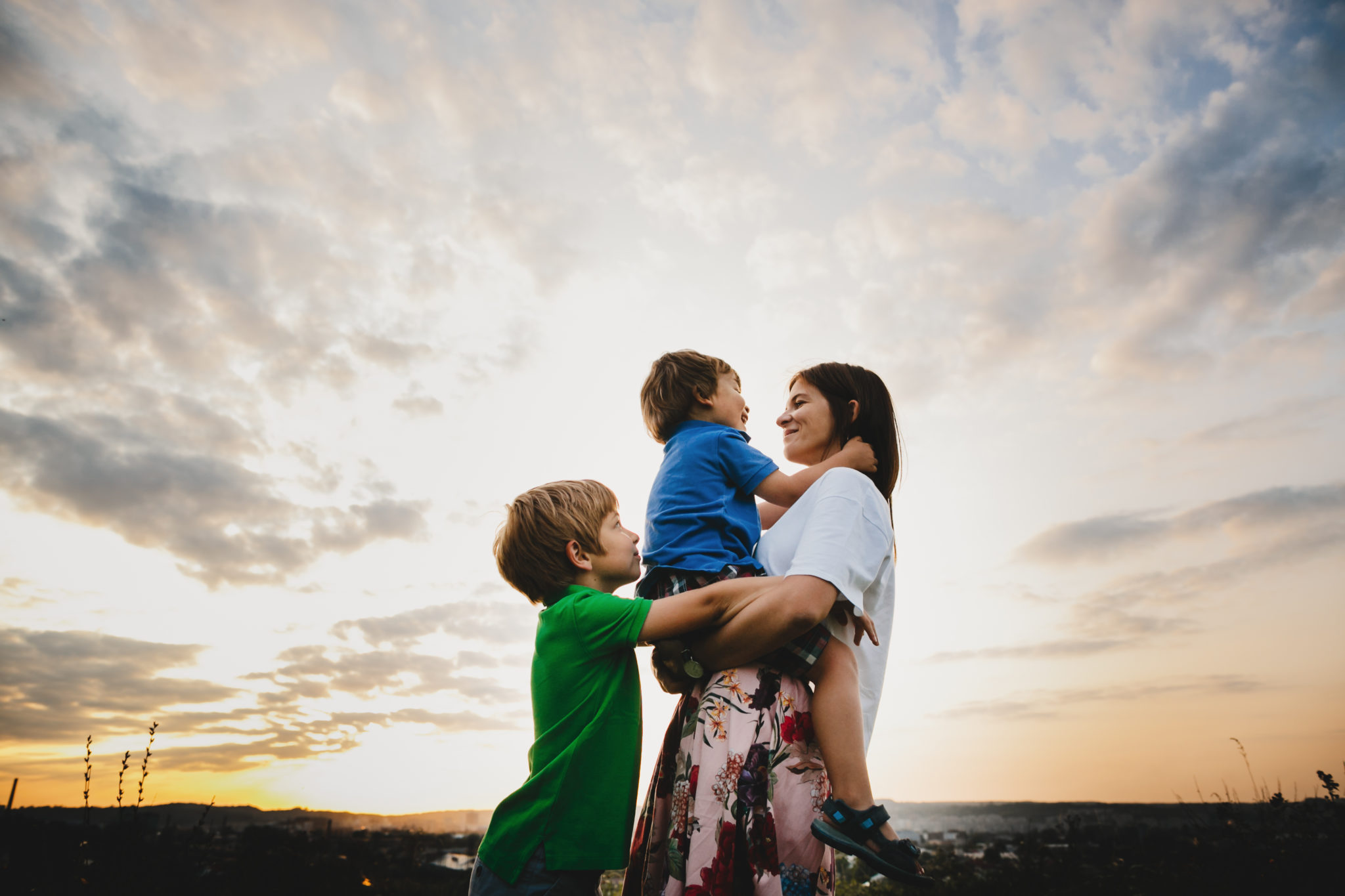 Mom Hugs With Her Two Little Sons Tender Standing In The Rays Of