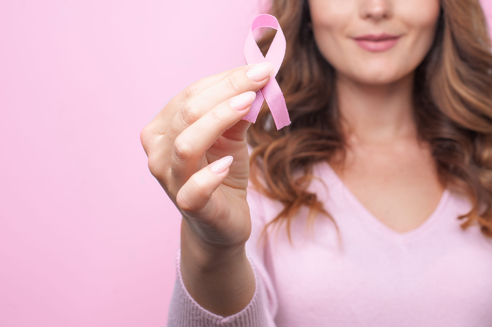 Woman In Pink Sweater With Pink Ribbon Supporting Breast Cancer Awareness Campaign